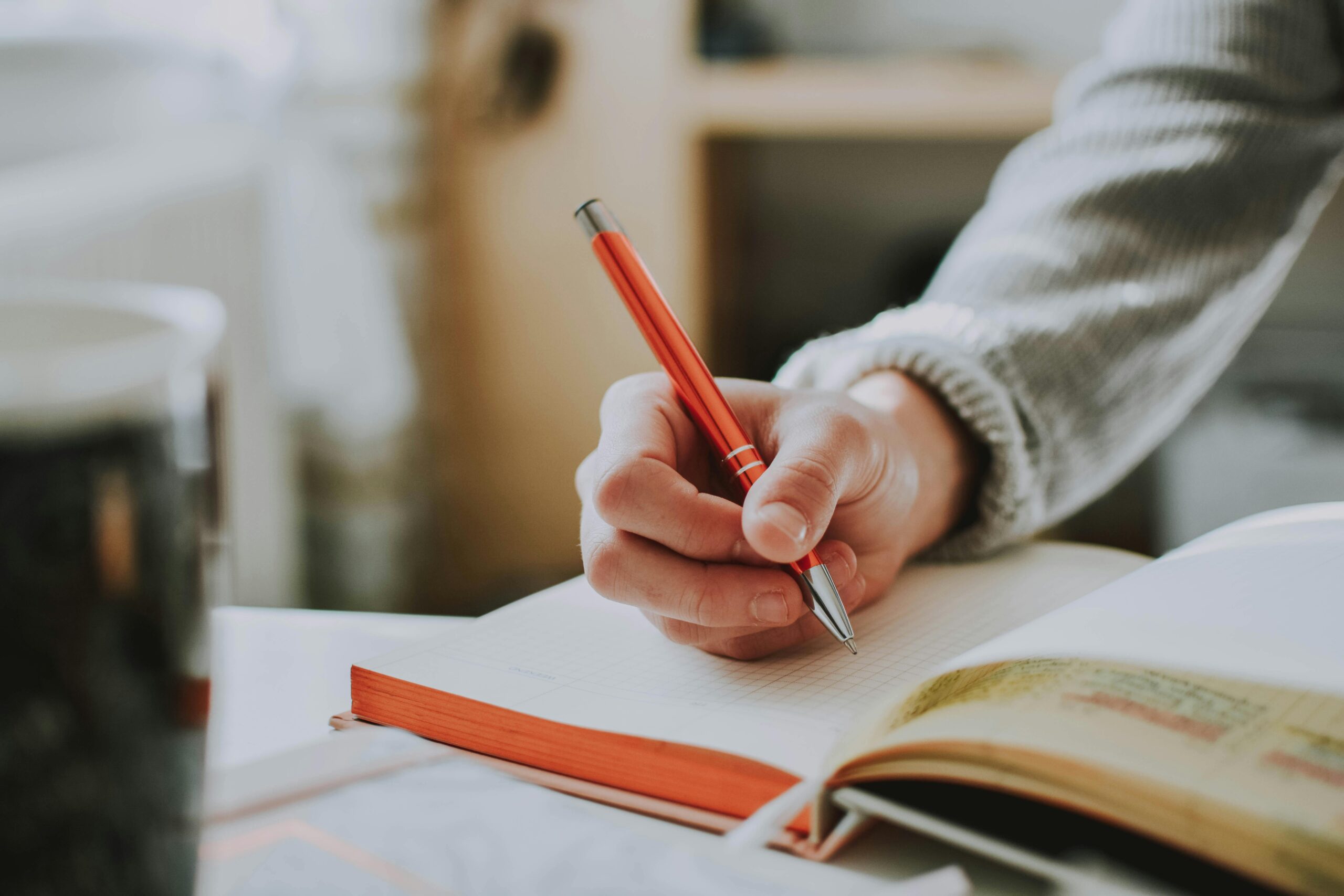 An open book with pen in hand, representing self-study or the fourth niyama, Svadyaya.